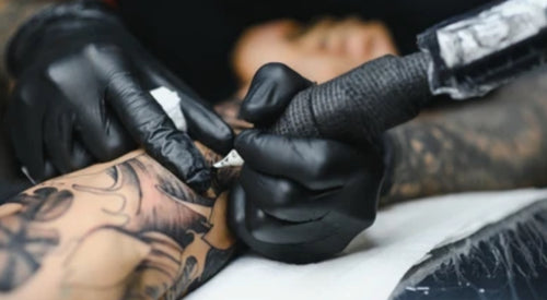 Gloved hands holding a tattoo machine